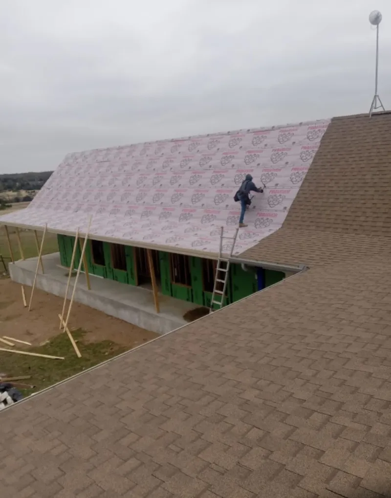 Worker preparing underlayment for a metal roof installation in Norfolk